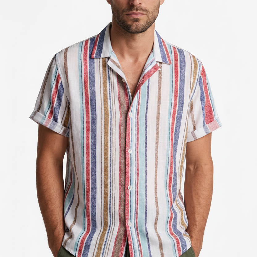 A man wearing a short-sleeve button-up shirt with vertical multicolor stripes in red, blue, beige, and white, paired with a beige baseball cap and olive green pants, against a plain white background.
