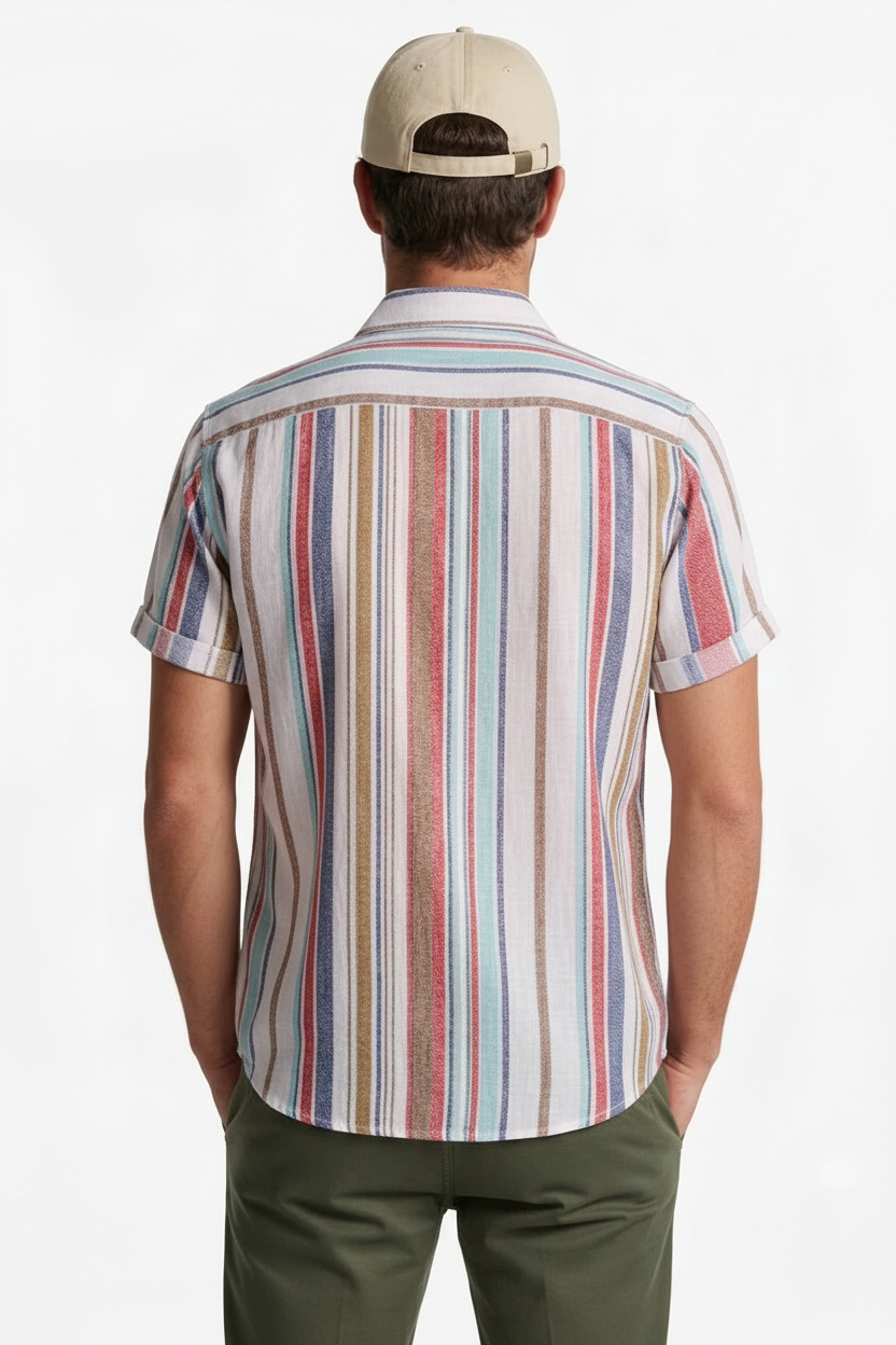 A man viewed from behind wearing a short-sleeve button-up shirt with vertical multicolor stripes in red, blue, beige, and brown, paired with a beige baseball cap and olive green pants, against a plain white background.